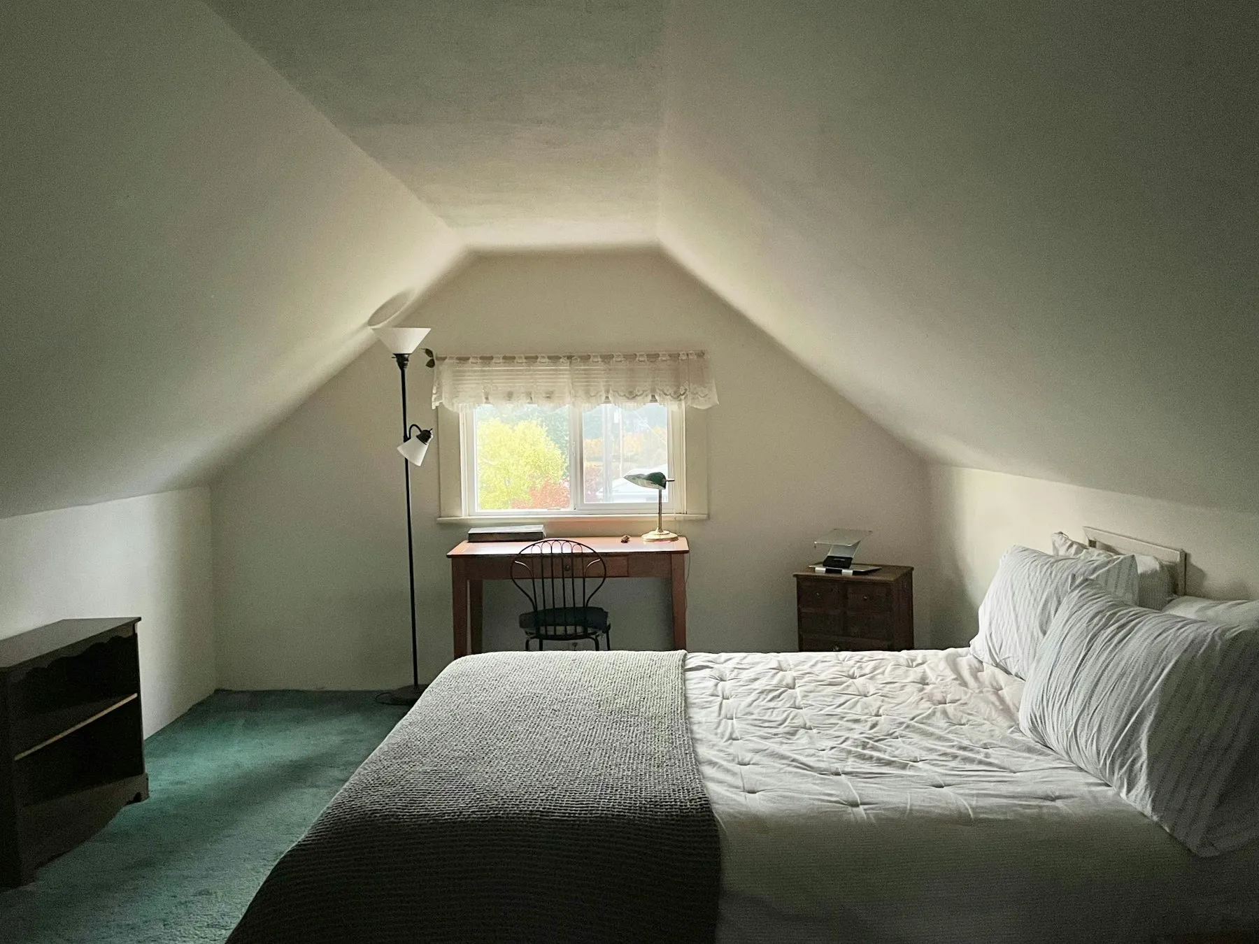 Converted loft bedroom with a large window and sloped ceiling