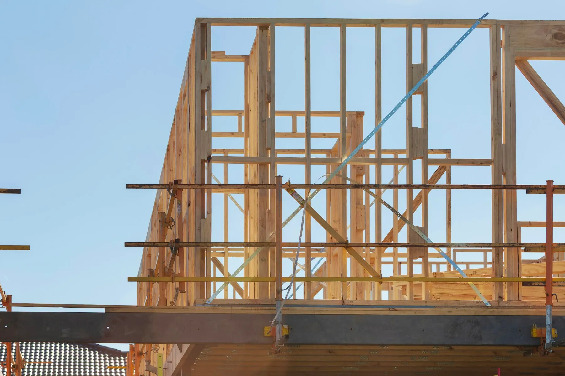 Timber frame of a new house under construction, wrapped in scaffolding